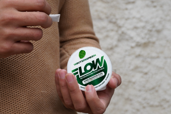 Hand pulling a pouch from a FLOW Wintergreen can