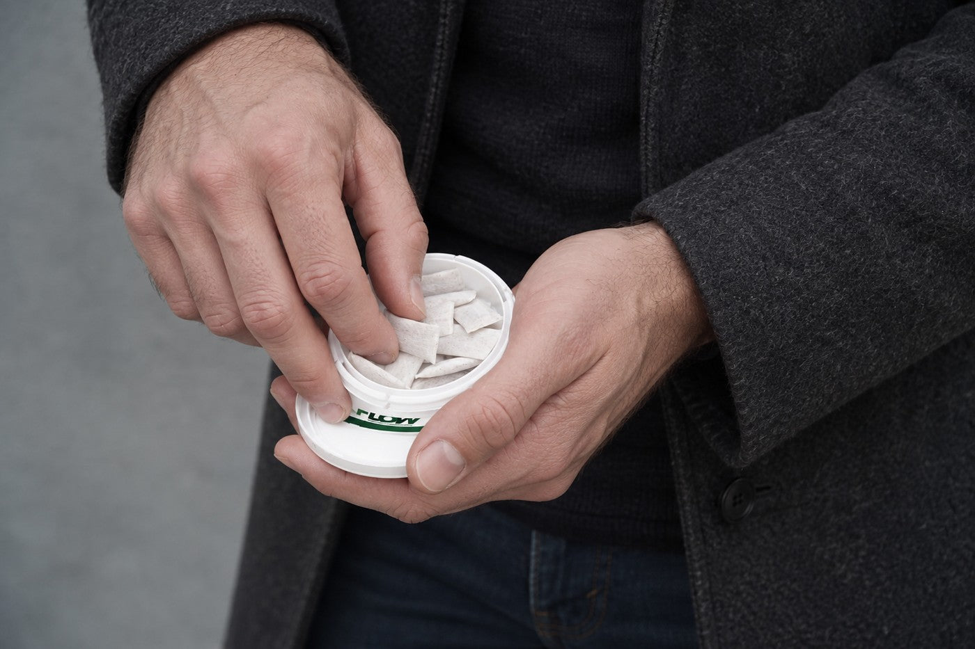 Hand taking a pouch from an open FLOW can